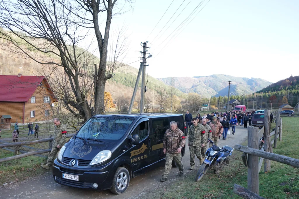 Військові та люди йдуть сільською дорогою в горах