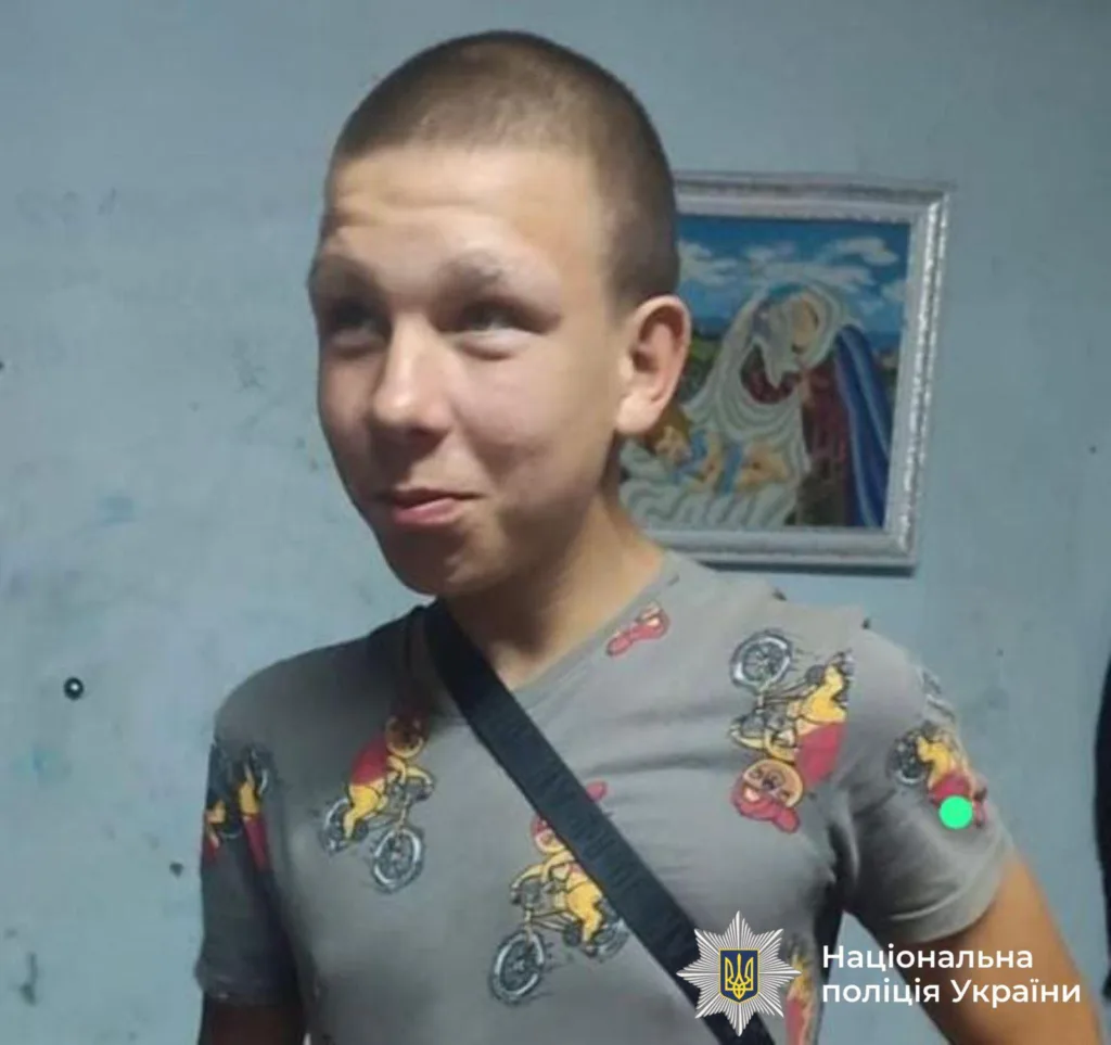 Підліток у сірій футболці з малюнками, усміхається