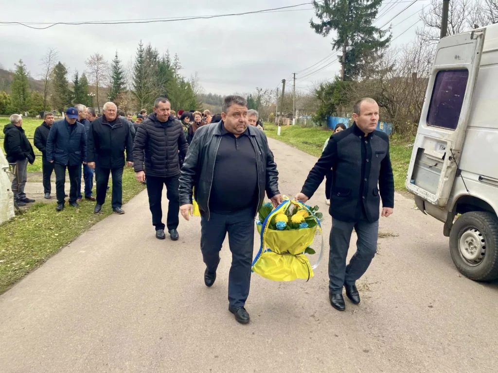 Чоловіки несуть квіти на вулиці села