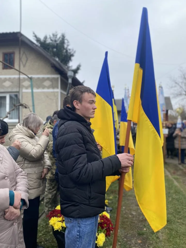 Люди з українськими прапорами на вуличній церемонії