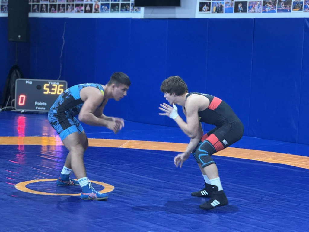 Двоє борців змагаються на синьому килимі