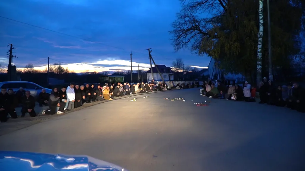 Люди на колінах уздовж дороги ввечері