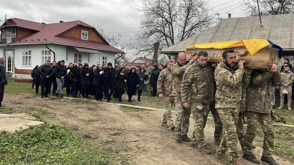 Військові несуть труну, люди йдуть за ними