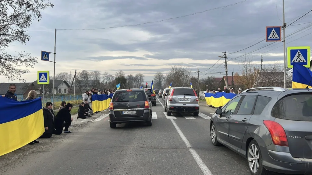 Люди з українськими прапорами вздовж дороги