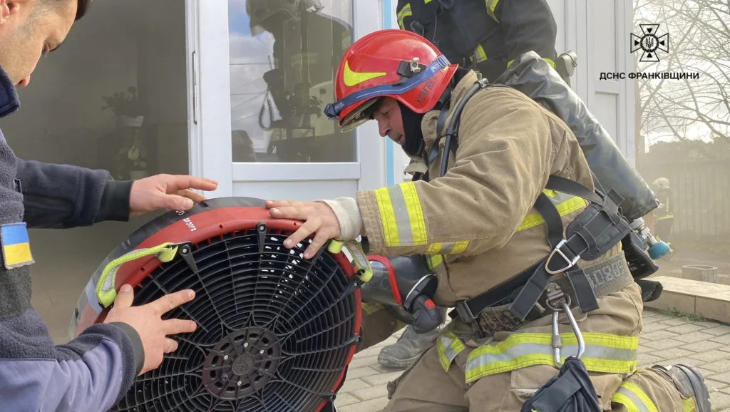 Пожежники налаштовують вентилятор біля будівлі
