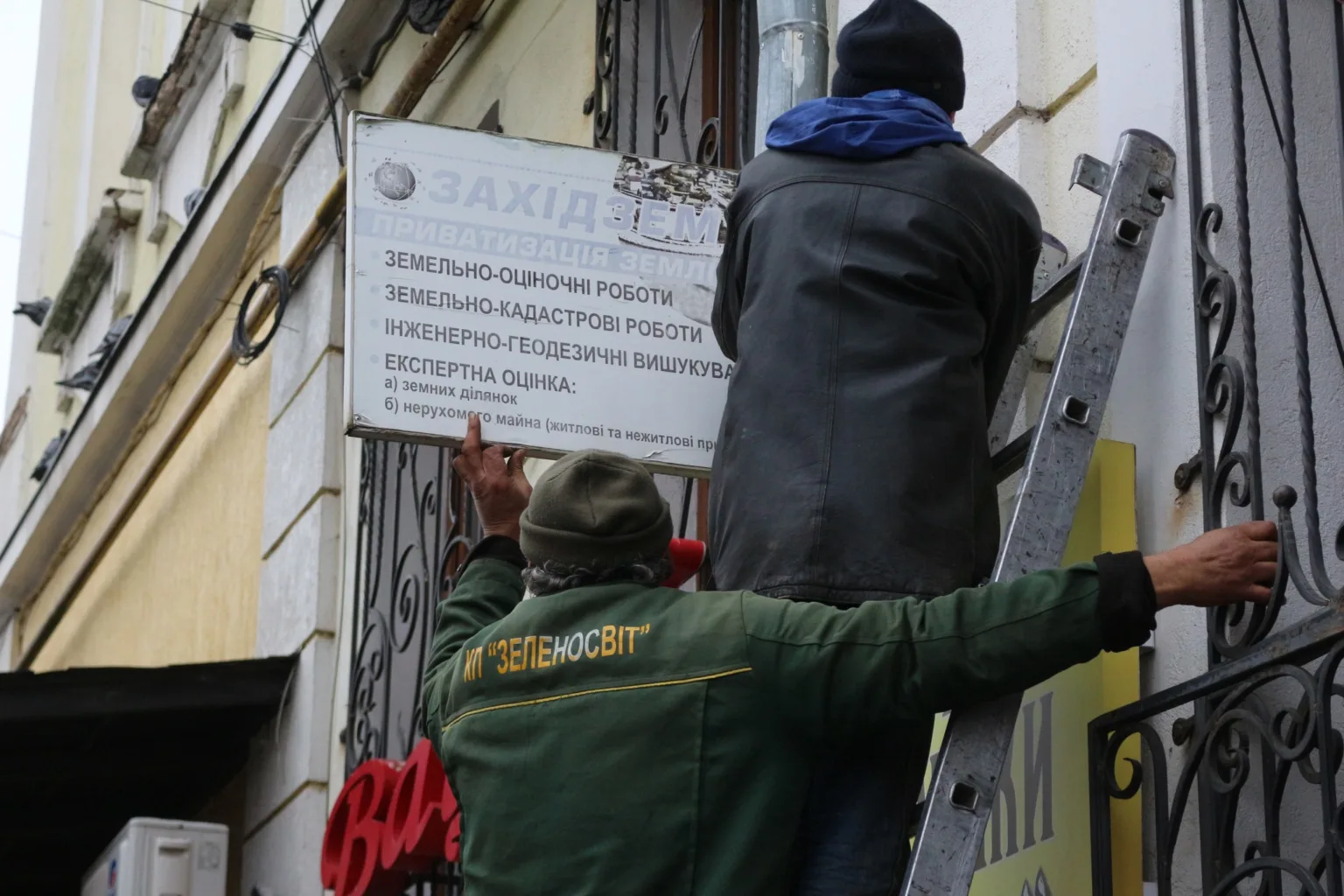 Робітники встановлюють рекламну вивіску на будівлі