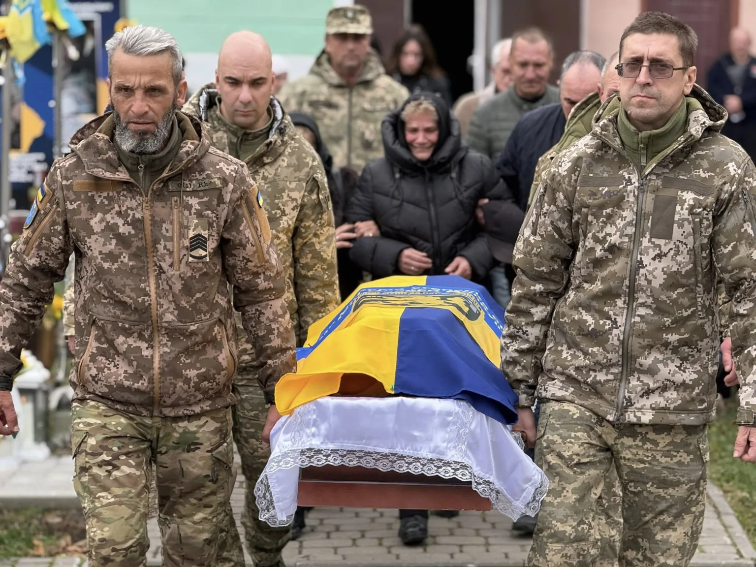 Військові несуть труну, вкриту українським прапором