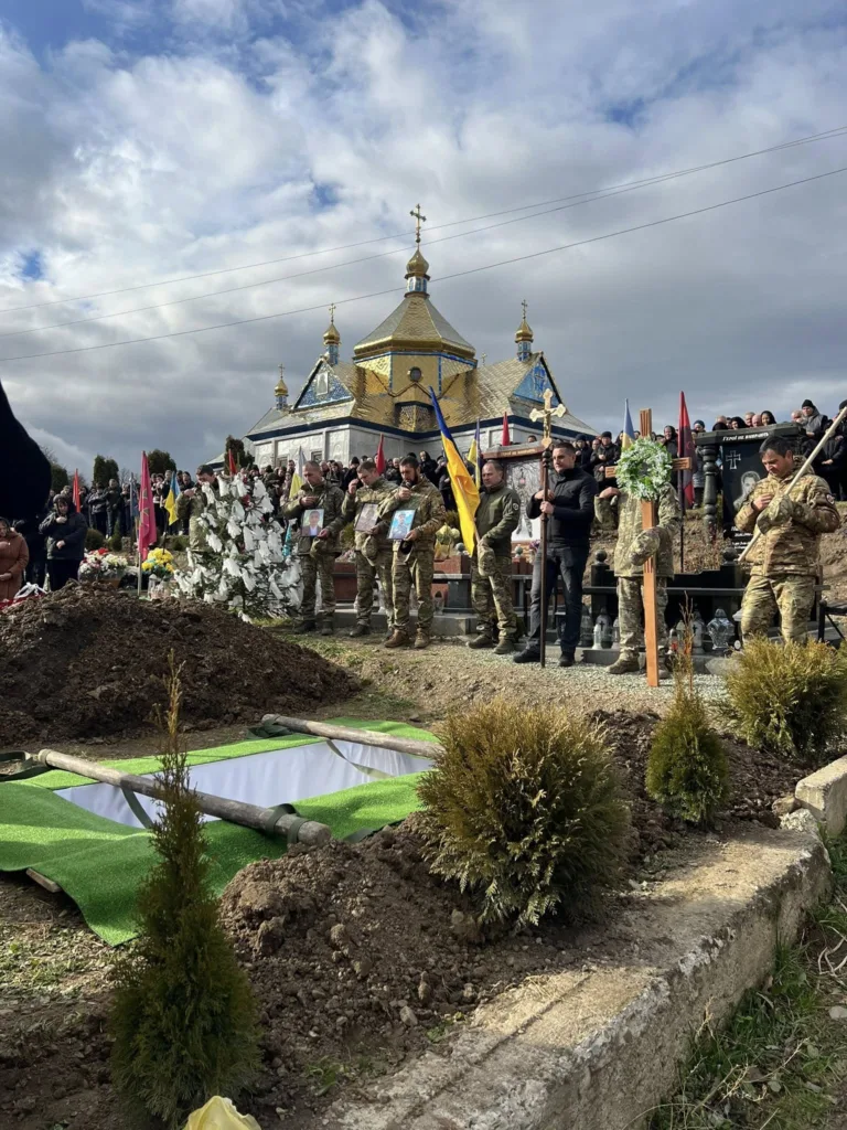 Похорон військових біля церкви з прапорами України