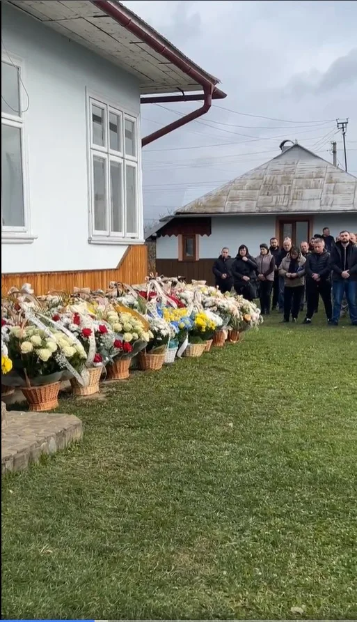 Люди біля будинку з квітами на подвір'ї