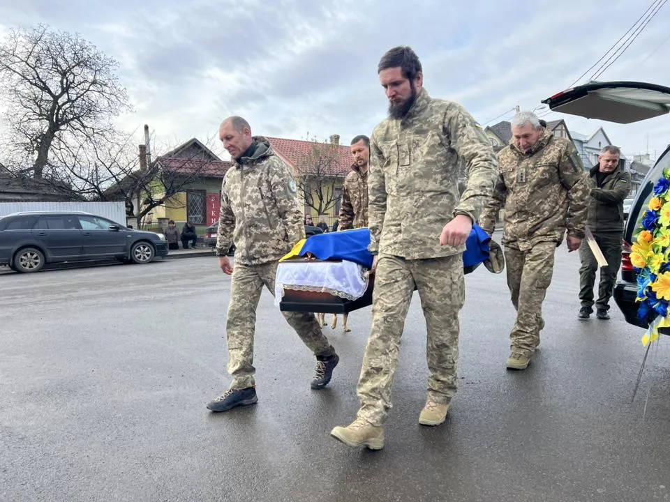 Військові несуть труну з українським прапором