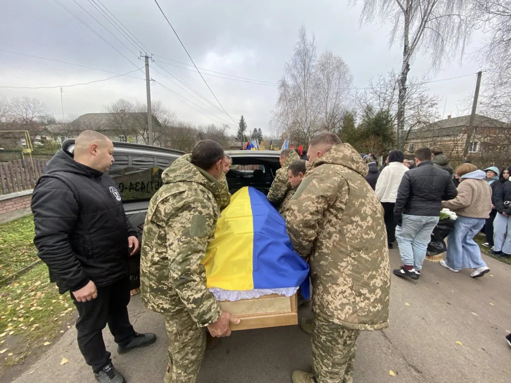 Військові несуть труну, накриту прапором України