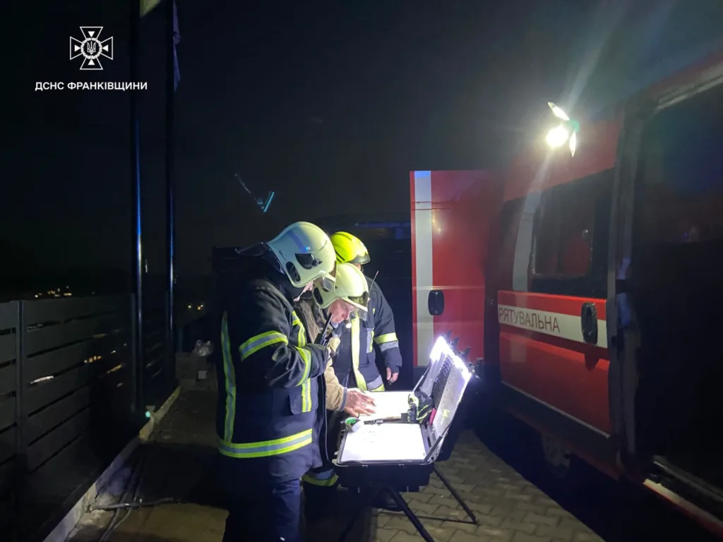 Рятувальники працюють біля пожежного автомобіля вночі