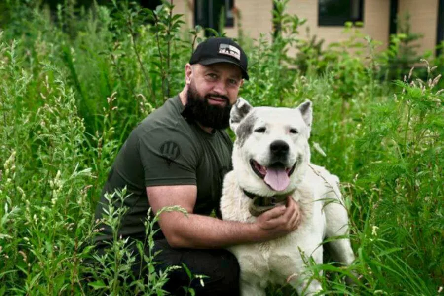 Чоловік обіймає великого собаку на природі
