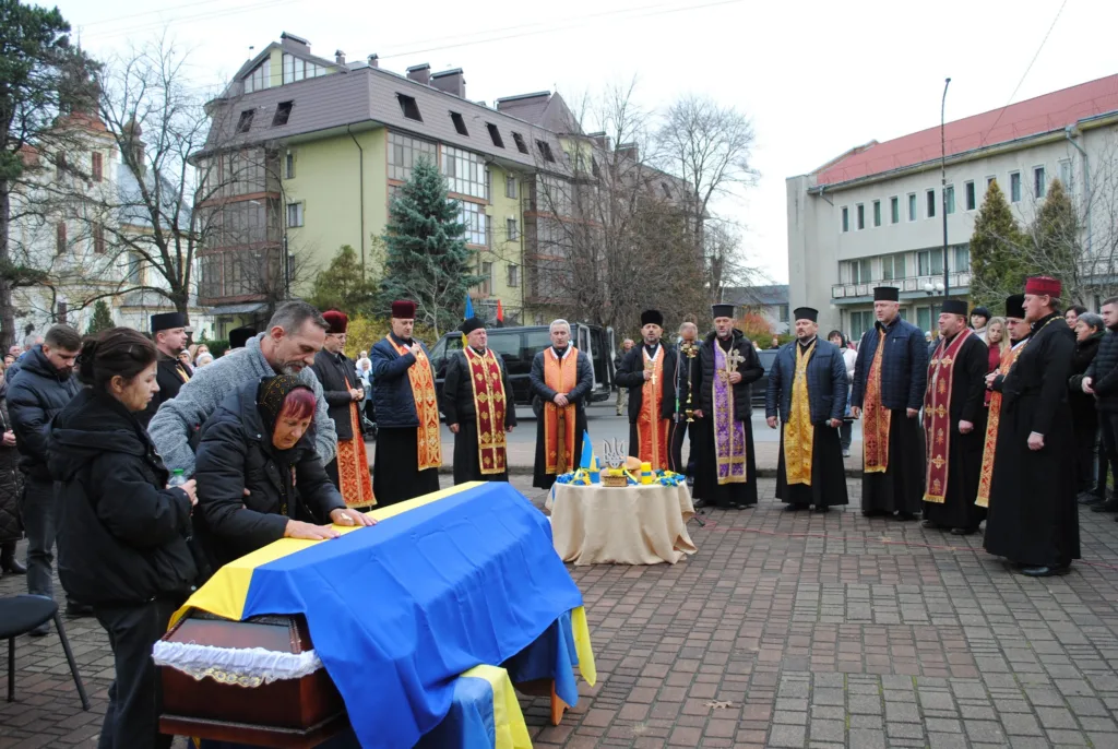 Похоронна церемонія з українським прапором та священниками