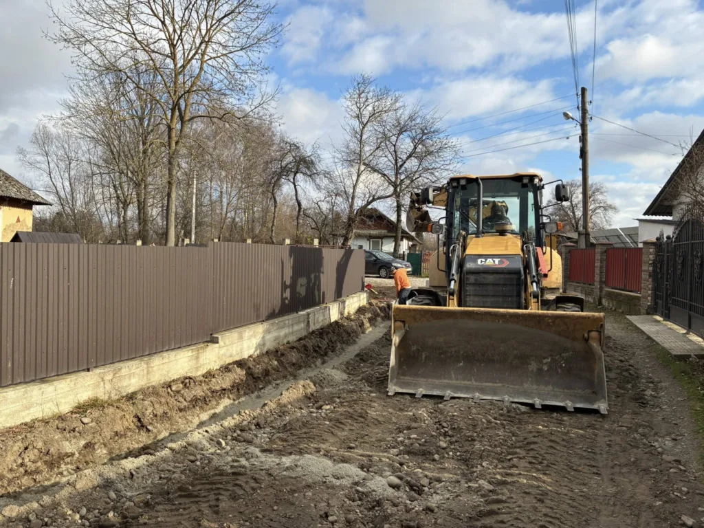 Бульдозер ремонтує ґрунтову дорогу біля житлових будинків