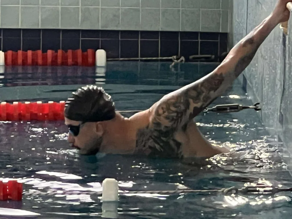 Плавець тренується у басейні перед стартом