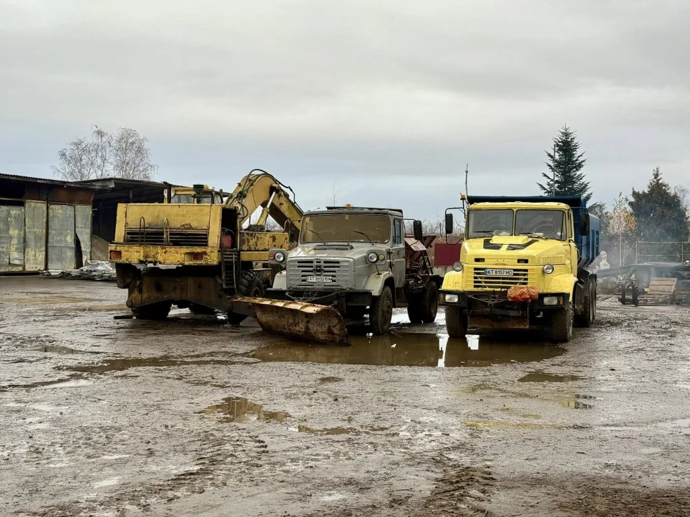 Вантажівки та екскаватор на брудному майданчику