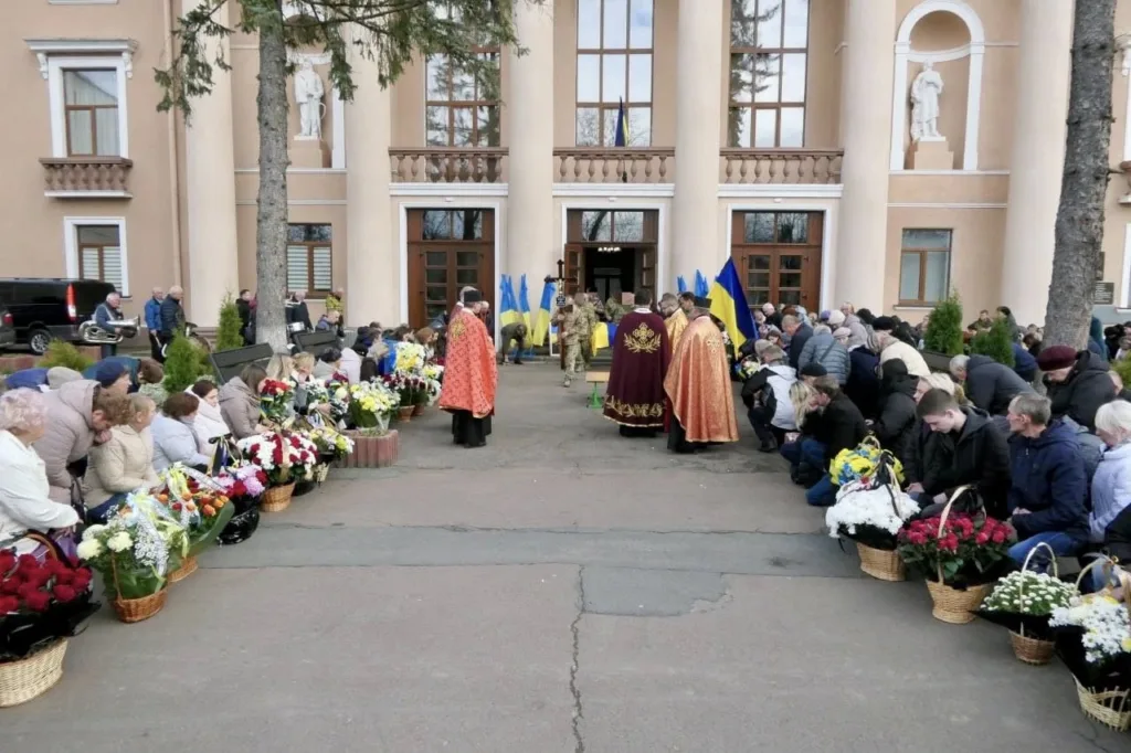 Прощання з військовим біля будівлі з прапорами України