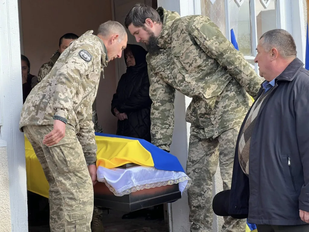 Військові несуть труну, накриту прапором України