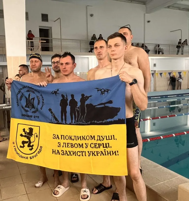 Плавці тримають прапор Галицької бригади біля басейну