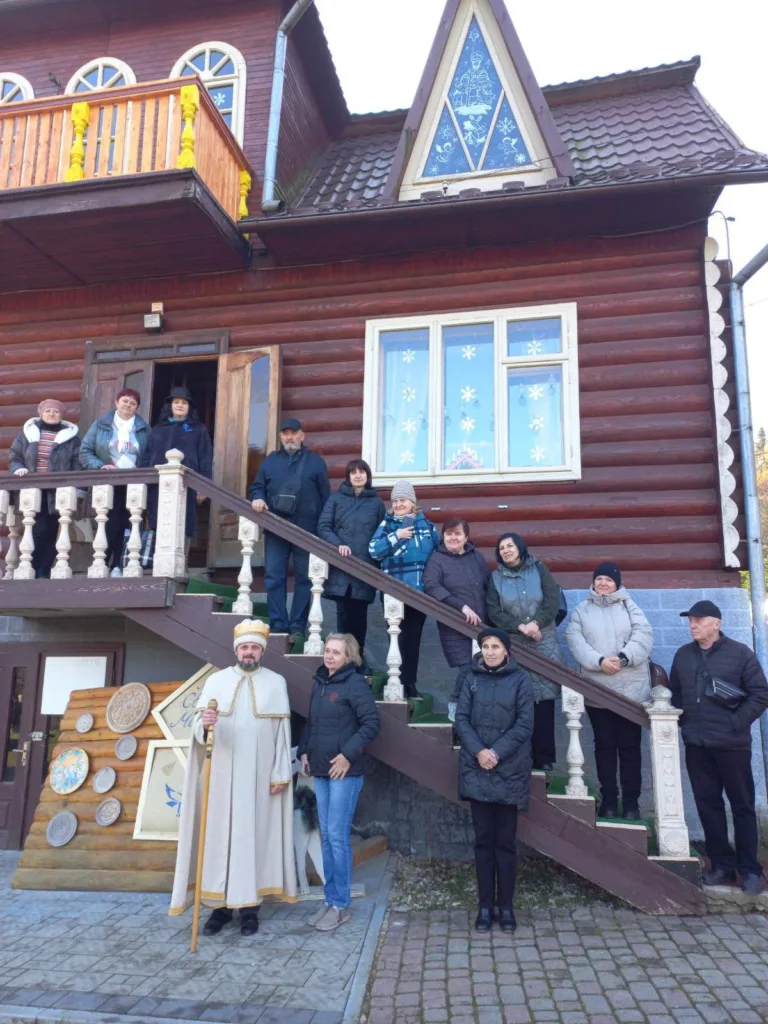 Група людей біля дерев'яного будинку в Україні