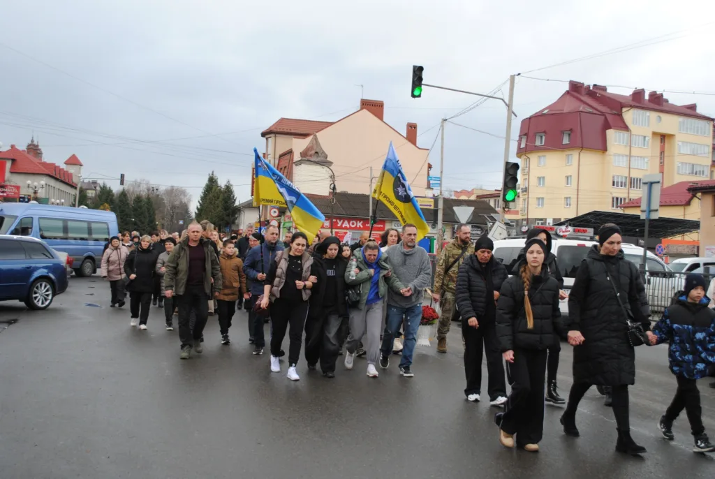 Люди йдуть вулицею з українськими прапорами
