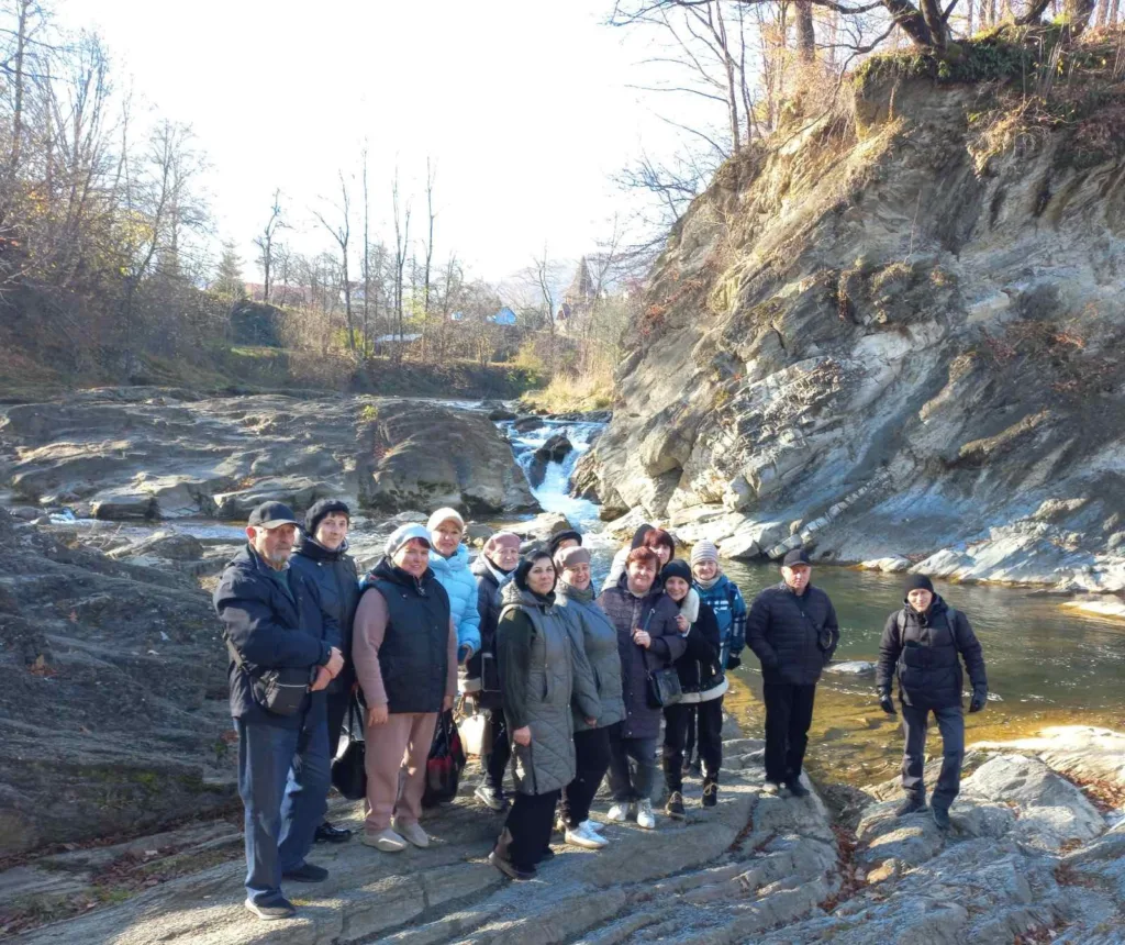 Група людей біля гірського водоспаду восени