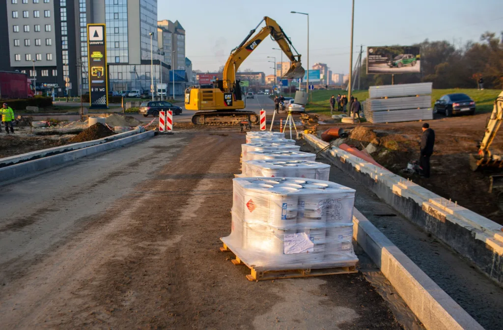 Будівництво дороги з екскаватором і матеріалами
