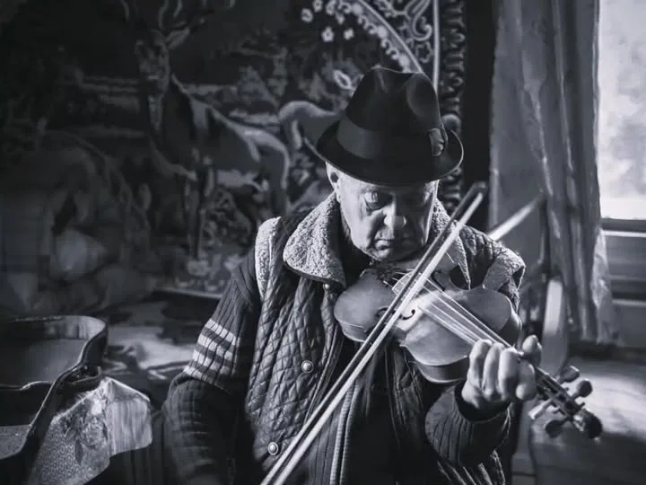 Чоловік грає на скрипці в кімнаті