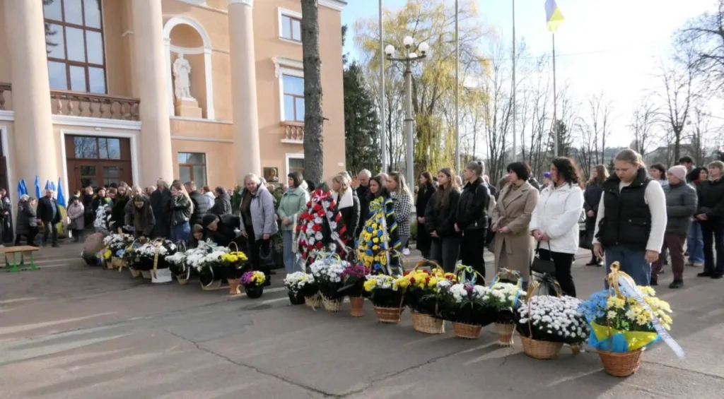 Люди з квітами на меморіальній церемонії в Україні