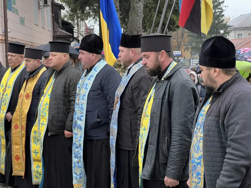 Священники на вуличній церемонії з прапорами України