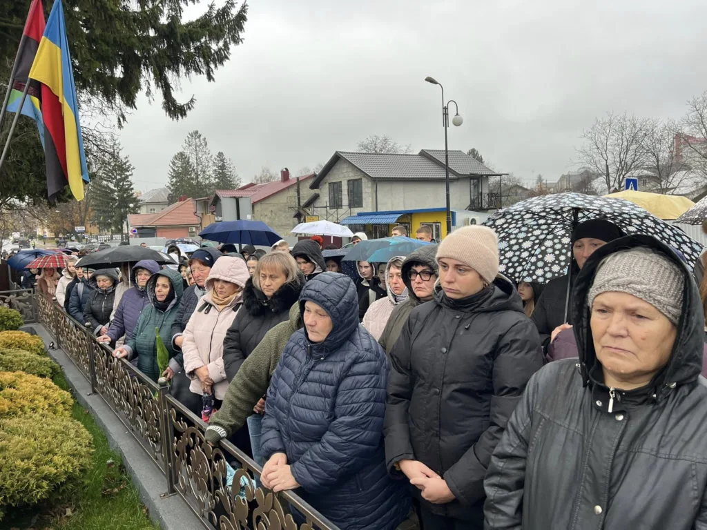 Люди під парасолями стоять на вулиці під дощем