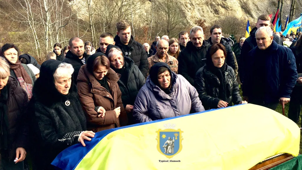 Люди оплакують героя під українським прапором