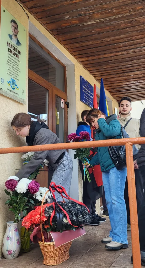 Люди покладають квіти до меморіальної дошки героя.