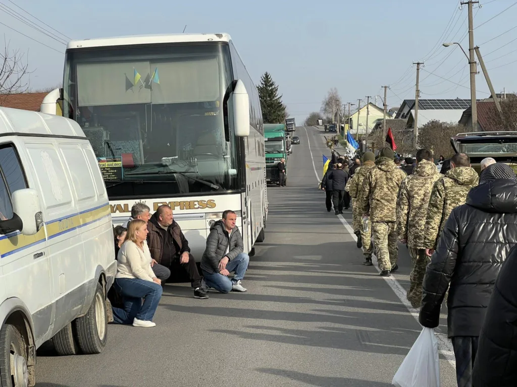Люди та військові на дорозі з українськими прапорами