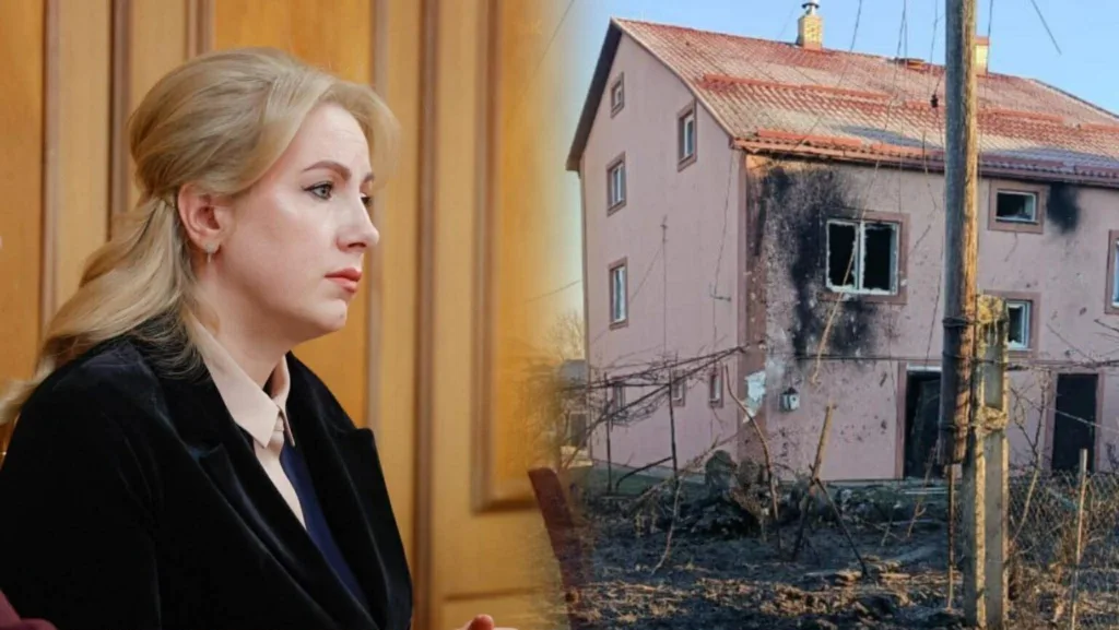 Жінка поруч із пошкодженим будинком після обстрілу