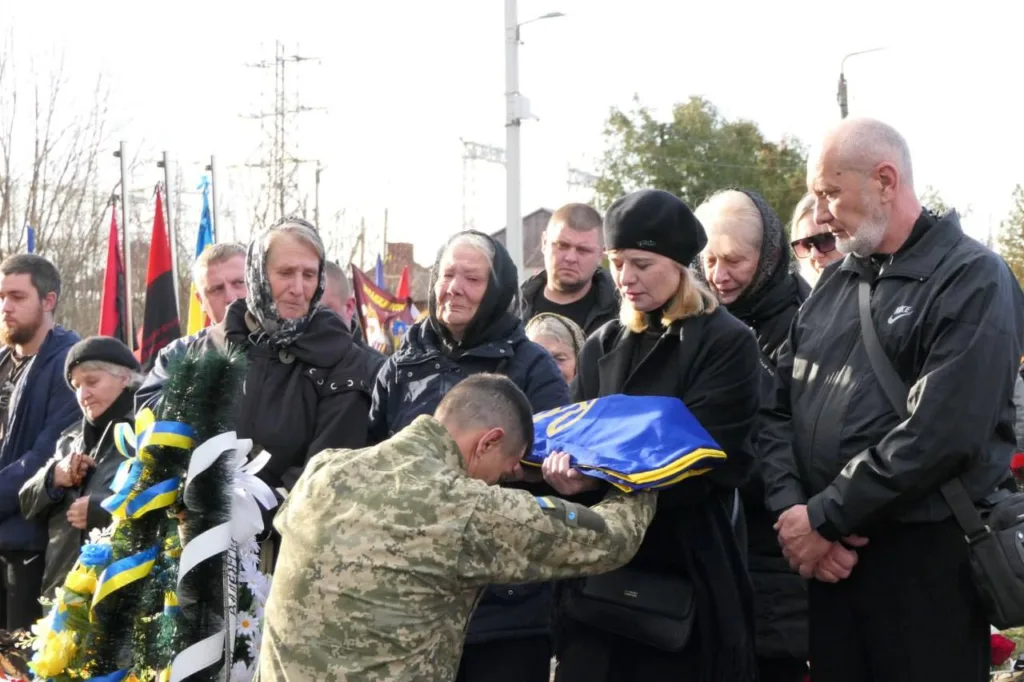 Прощання з військовим, родина тримає прапор України