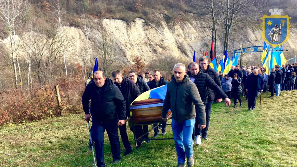 Похоронна процесія з українськими прапорами у горах
