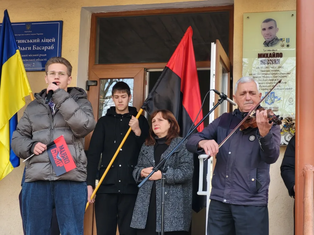 Люди виступають біля ліцею з прапорами України