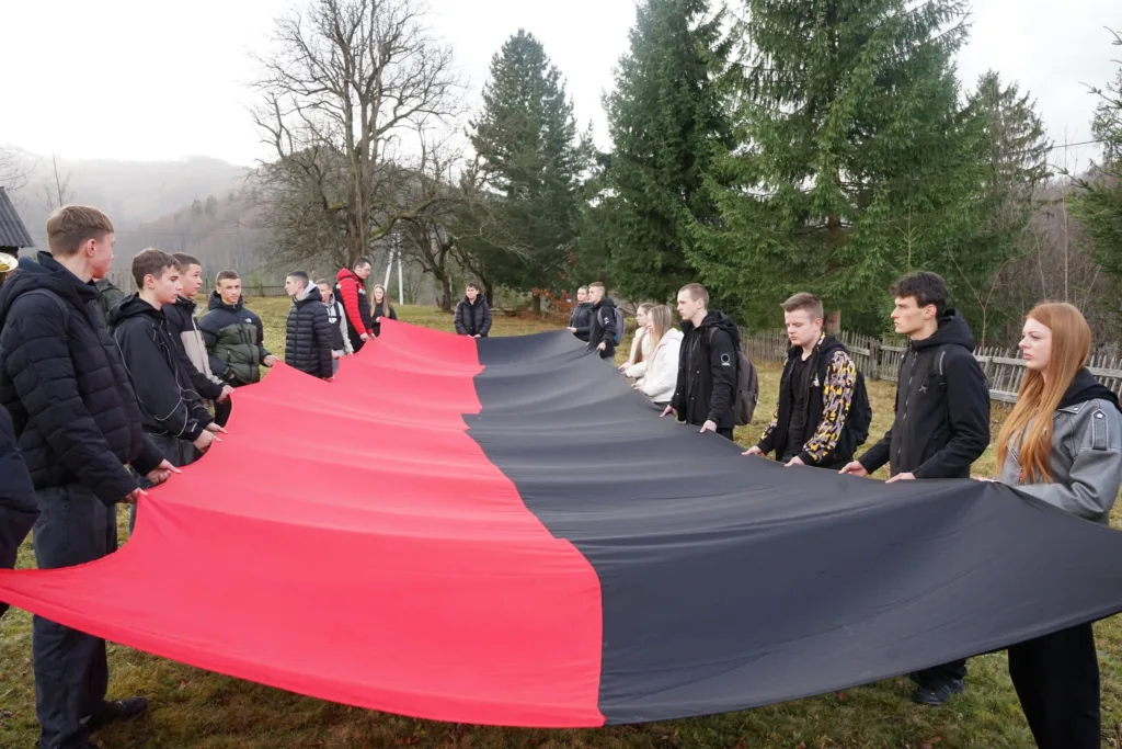 Молодь тримає великий червоно-чорний прапор на вулиці