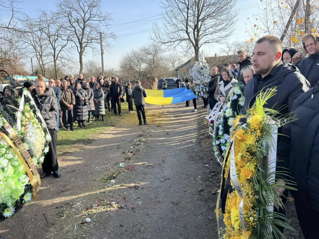 Похоронна процесія з українським прапором і вінками