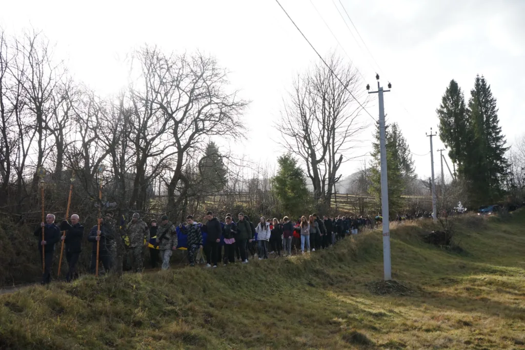 Люди йдуть сільською дорогою з прапором України