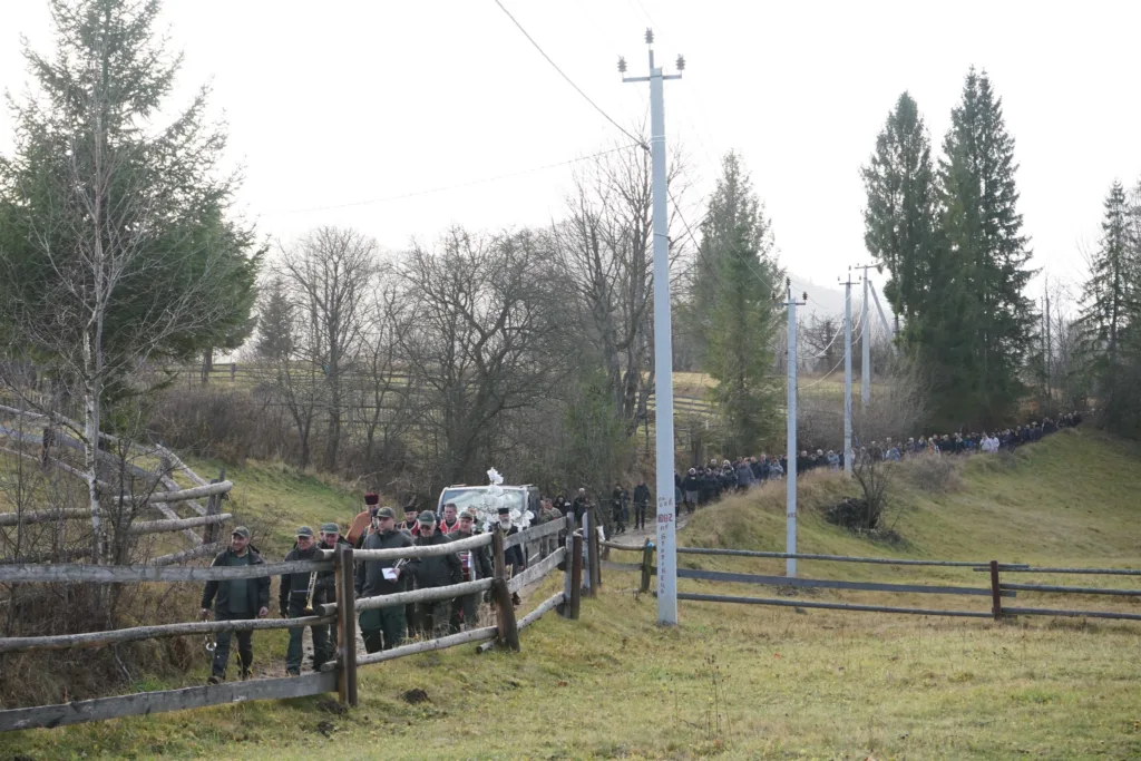 Процесія людей йде сільською дорогою серед природи