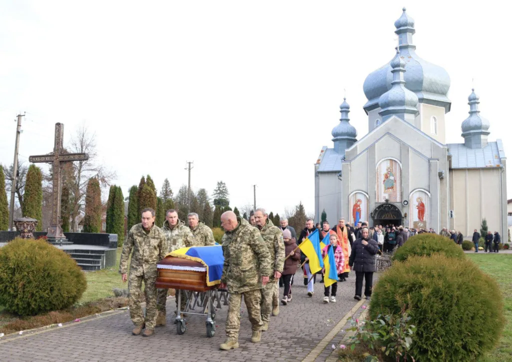 Військові несуть труну біля української церкви