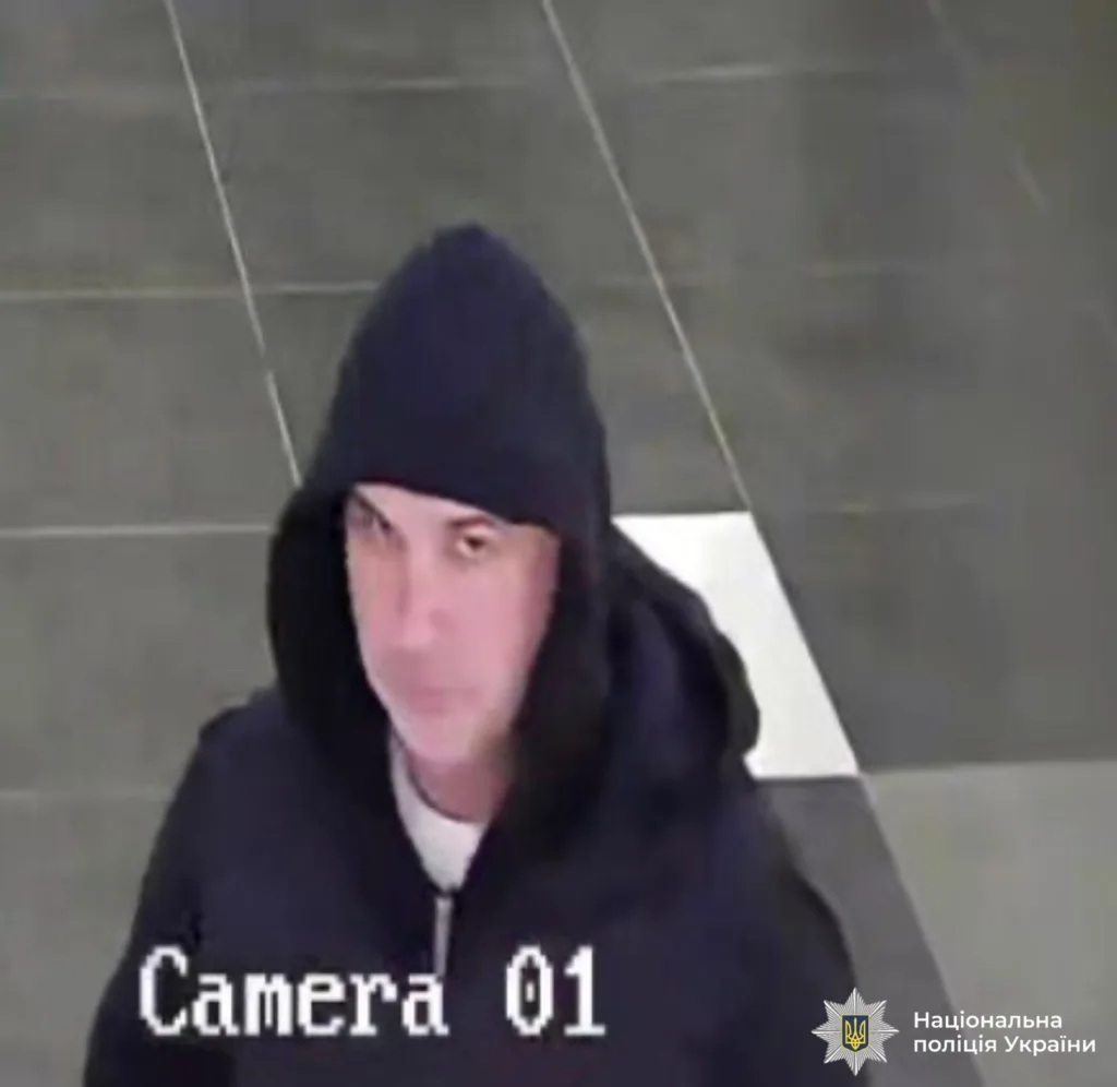 Людина в чорній худі перед камерою спостереження