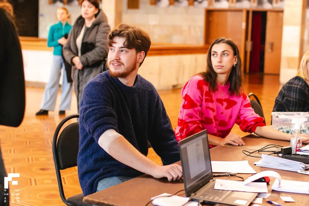 Люди працюють за столом з ноутбуком у залі