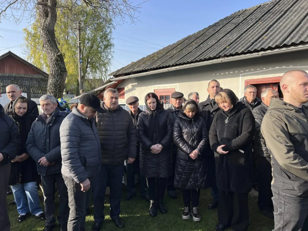 Люди стоять на вулиці під час поминальної події