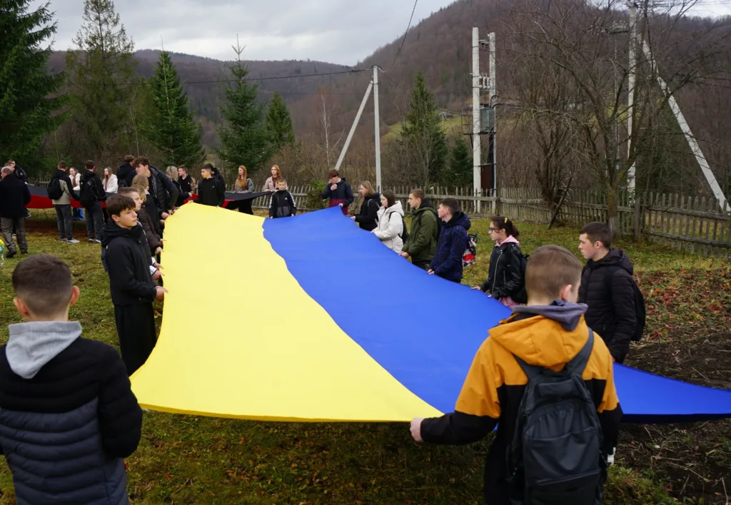 Люди тримають великий прапор України на природі