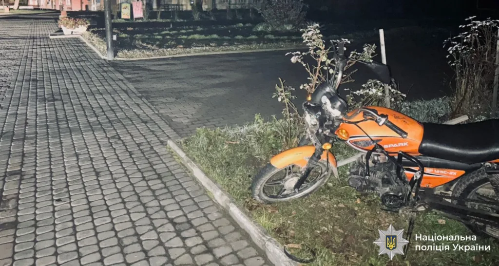 Помаранчевий мотоцикл біля тротуару вночі