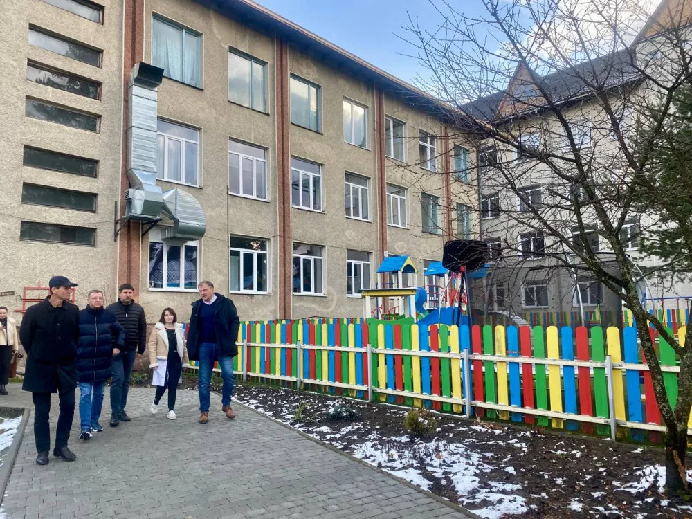 Люди йдуть біля школи з яскравим парканом